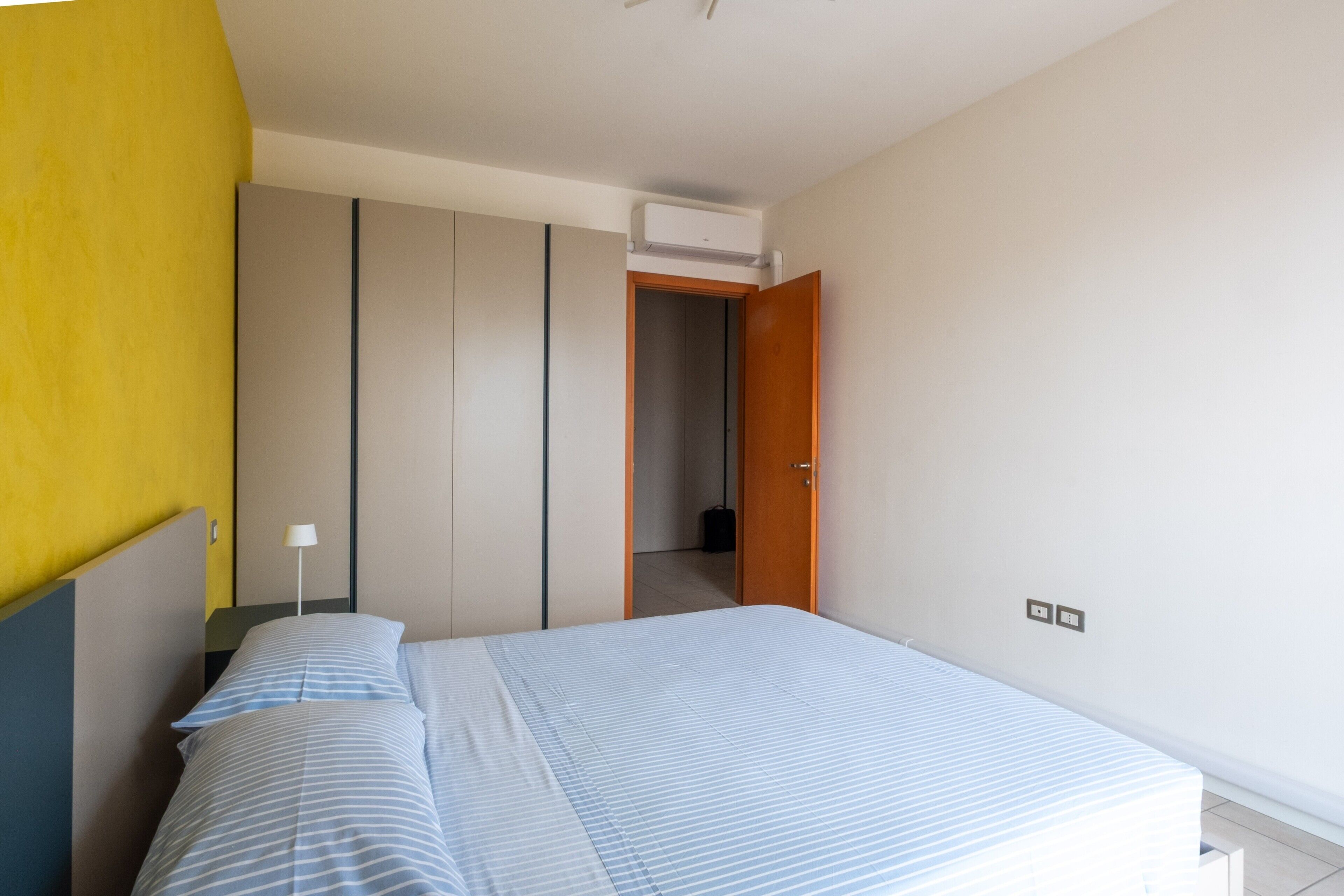 Ein Schlafzimmer mit Bett, Kleiderschrank und Klimaanlage.