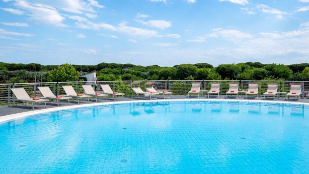 Ein Schwimmbecken mit Liegestühlen und blauem Himmel.