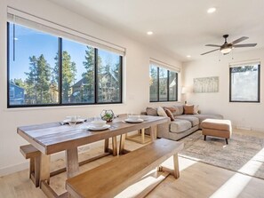 A modern living room with a wooden dining table, a sofa, and a ceiling fan. - Fraser Ridge Retreat 3 Bed 3.5 Bath - Sleeps 9 (Fraser)