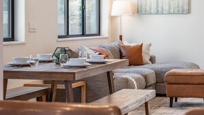 A dining area with a wooden table set for four, a sofa, and a painting on the wall. - Fraser Ridge Retreat | 3BR/3.5BA, Free WP Shuttle (Fraser)