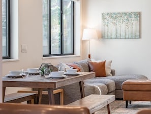 A dining area with a wooden table set for four, a sofa, and a painting on the wall. - Fraser Ridge Retreat 3 Bed 3.5 Bath - Sleeps 9 (Fraser)