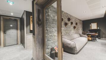 A modern living room with a stone wall, a sofa, and a wooden door.