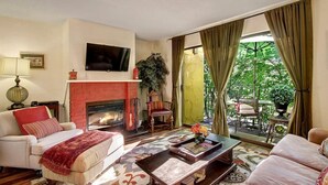 Una sala de estar con chimenea, televisor y vistas al exterior.