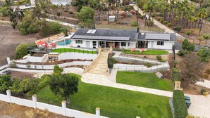 Une maison moderne dotée d’un grand jardin à l’avant, d’une piscine et d’un escalier menant à l’entrée.