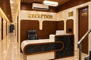 A reception area with a reception desk, a black leather chair, and a sign indicating a washroom. - Hotel Prem Ratan Residency Vrindavan (Vrindavan)