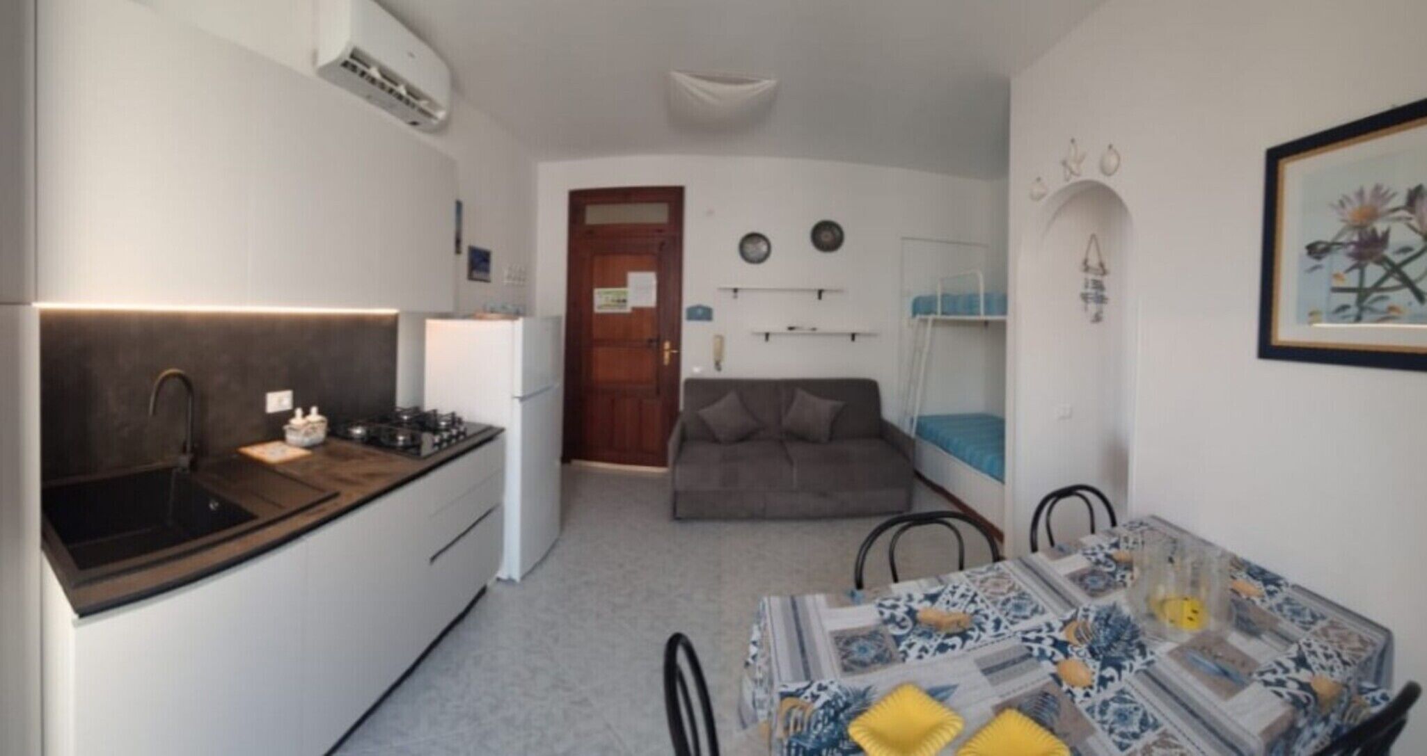 A compact kitchen with a sink, stove, and a dining area with a table and chairs.