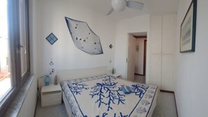 Makuuhuoneessa on sänky, ikkuna, kattotuuletin ja ovi, joka johtaa toiseen huoneeseen.