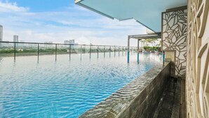 A rooftop infinity pool with a city view, a covered seating area, and a decorative wall. - Hovin by Kozystay - Tebet (Jakarta)