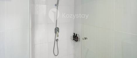 Un espacio de ducha moderno con ducha de mano, ducha fija y manguera de ducha.