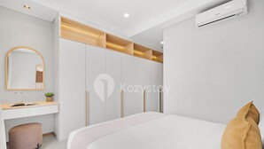 A modern bedroom with a bed, a bedside table, a mirror, and a wardrobe. - Hovin by Kozystay - Tebet (Jakarta)