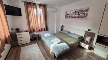 A modern bedroom with a bed, bedside tables, a TV, and a painting on the wall.