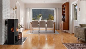 Een moderne woonkamer met een open haard, een eethoek en uitzicht op het omliggende landschap.