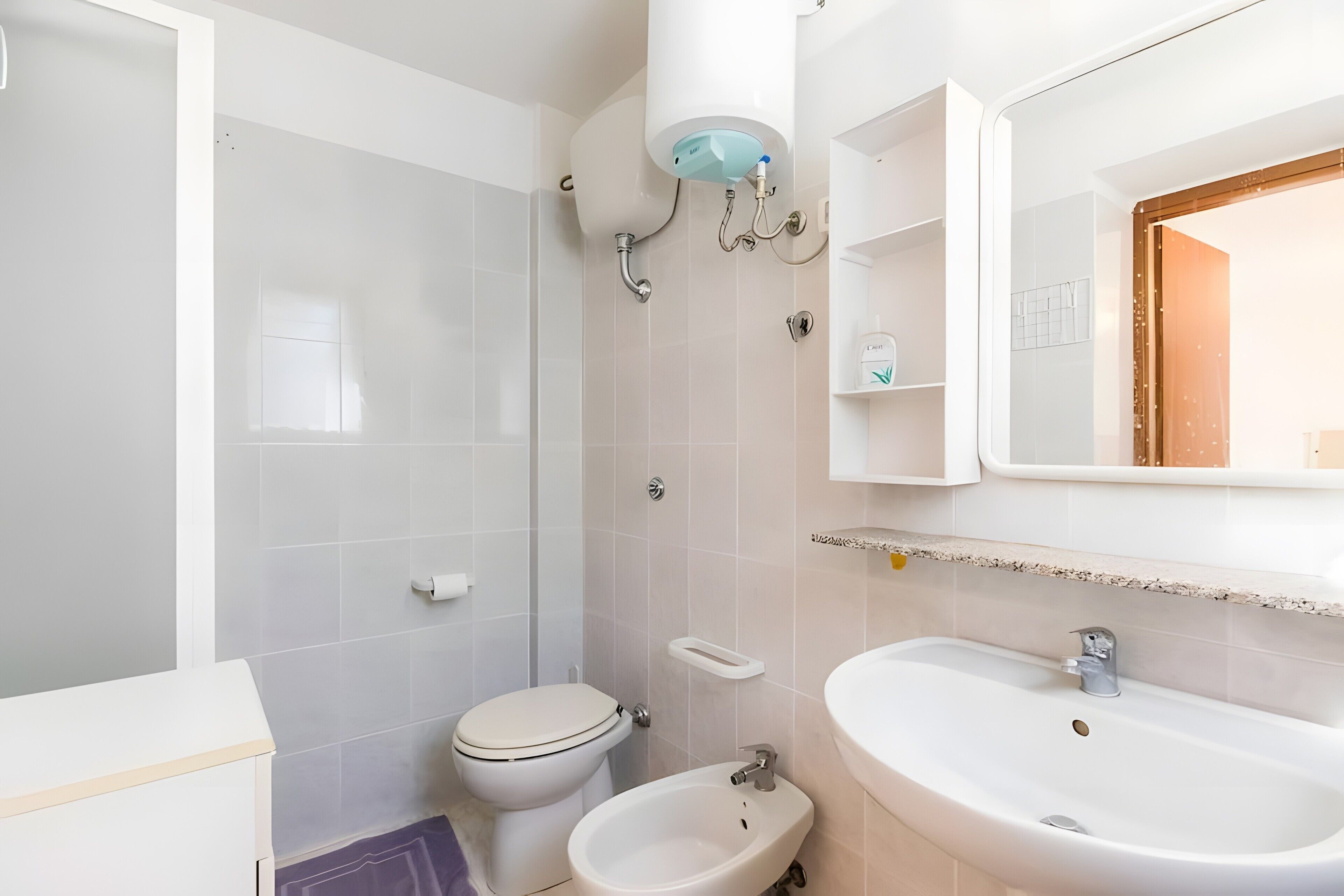 A bathroom with a toilet, bidet, sink, and a mirror above the sink.