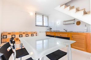 Una cocina moderna con una mesa de vidrio, armarios de madera y una estufa empotrada.