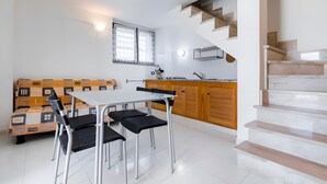 A modern kitchen with a dining table and chairs, a wooden bench, and a staircase. - Apartment 'Spiaggia E Relax' with Private Terrace, Garden and Air Conditioning (Calasetta)