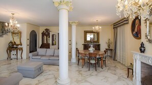 Uma sala de estar espaçosa com piso de mármore, uma mesa de jantar redonda, um sofá e uma lareira.