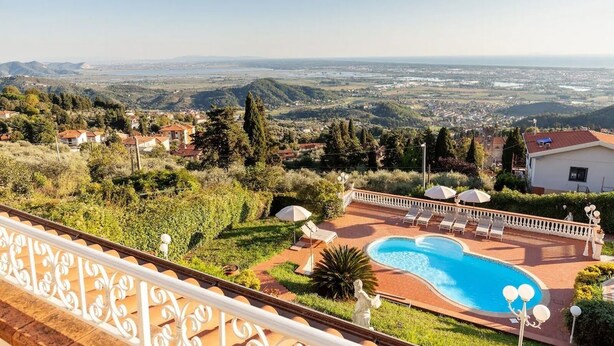 Área da piscina com vista para a paisagem urbana e colinas ao fundo.