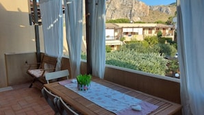 A balcony with a wooden table, chairs, and a potted plant.