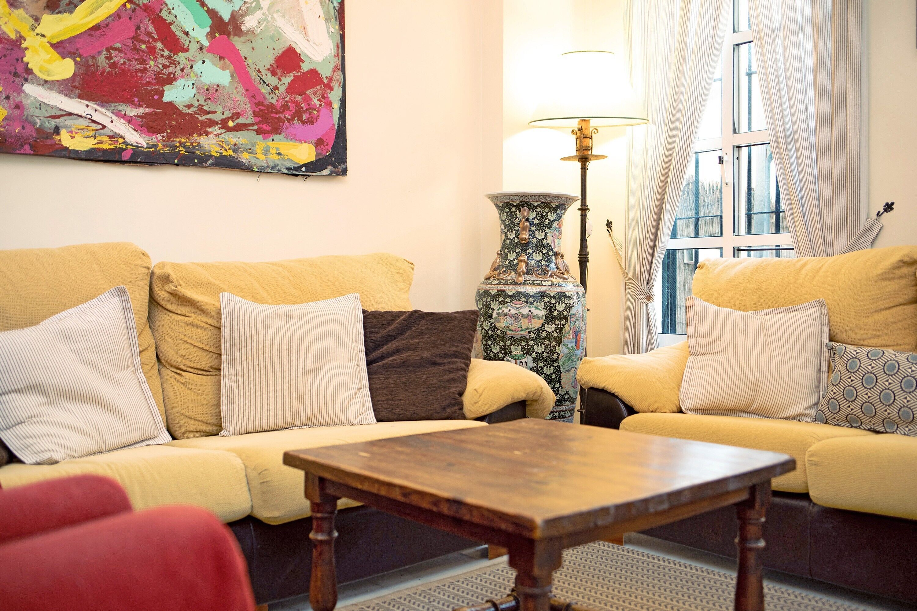 A living room with a sofa, a table, a lamp, and a window with curtains.