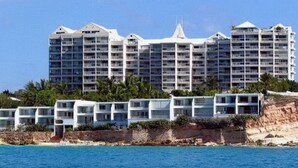 A coastal hotel with multiple buildings, including a prominent white structure with a pointed roof and several smaller white buildings with balconies. - Waterfront luxury villa in Saint-Martin (Sint Maarten)