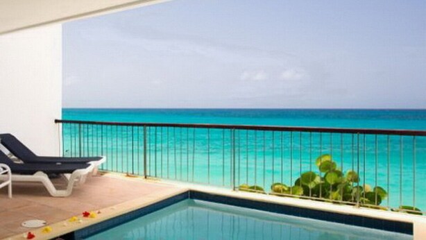 A poolside area with a view of the ocean, a pool, and lounge chairs. - Waterfront luxury villa in Saint-Martin (Sint Maarten)