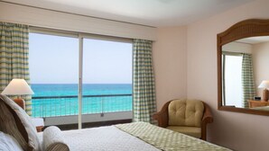 A hotel room with a bed, a chair, a large window with a view of the ocean, and a mirror on the wall. - Waterfront luxury villa in Saint-Martin (Sint Maarten)