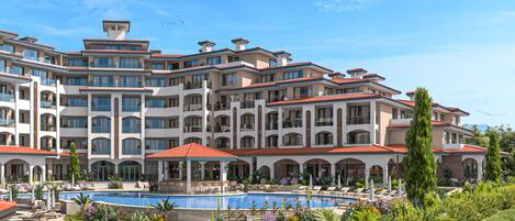 A multi-story hotel with a swimming pool, outdoor seating, and lush landscaping.