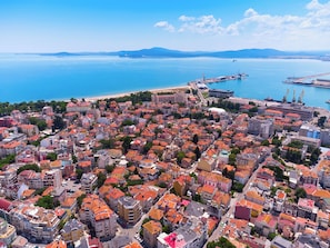 An aerial view of a coastal city with dense urban development, a prominent port with cranes, and a beach in the background. - Sanders Solemare - Cute 1 Bdr Apt With Balcony (Pomorie)