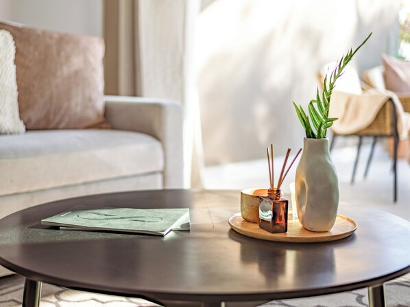 Une table ronde avec un carnet, un petit vase contenant des plantes vertes et un chandelier.