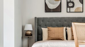 A neatly arranged bedroom with a tufted headboard, a bedside table with a lamp, and a chair with a woven backrest. - Sanders Solemare By the Sea - Close to Sunny Beach and Nessebar (Pomorie)