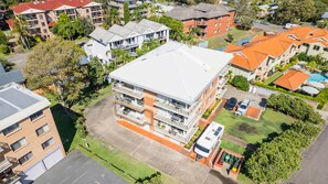 A multi-story residential building with balconies, a swimming pool, and a parking area. - Seaspray Sands Coastal Retreat in Nelson Bay (Nelson Bay)