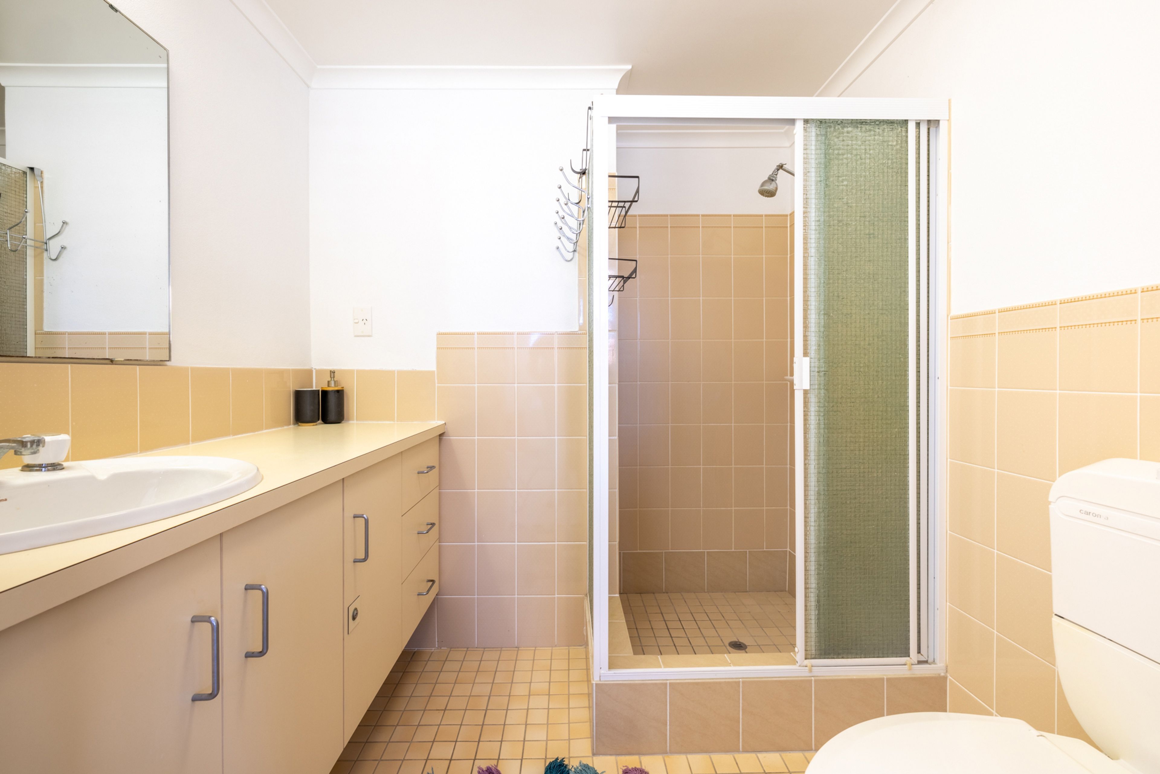 A bathroom with a sink, mirror, cabinets, and a shower area.