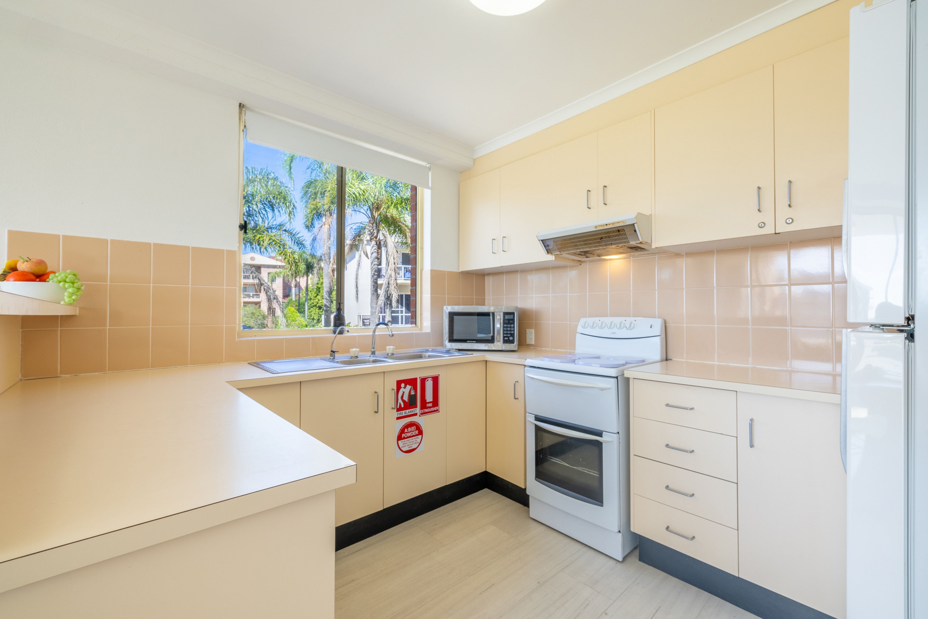 A kitchen with a microwave, oven, and a window with a view of palm trees.