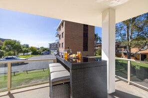 A balcony with outdoor seating, a table with drinks, and a view of a parking lot and buildings. - Seaspray Sands Coastal Retreat in Nelson Bay (Nelson Bay)