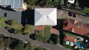 An aerial view of a property with a swimming pool, a parking lot, and a building with a sloped roof. - Seaspray Sands Coastal Retreat in Nelson Bay (Nelson Bay)
