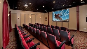 A conference room with rows of red and black chairs, a large screen, and a patterned carpet.