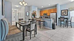 A modern kitchen with wooden cabinets, a central island, and a dining area with a sofa and chairs.