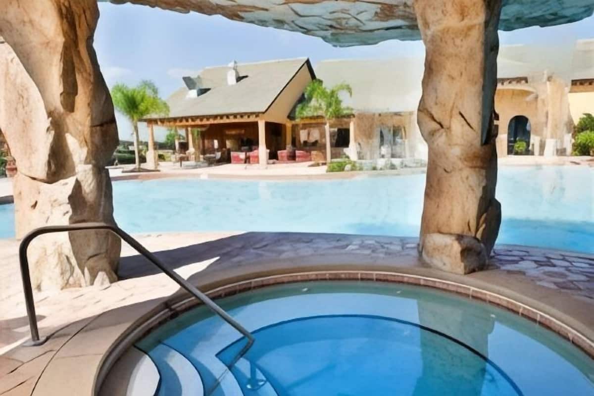 Un jacuzzi con vista despejada a una piscina y un edificio al fondo.