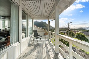 Ein überdachter Balkon mit Holzboden, einem Stuhl und einem Tisch mit einem Korb.