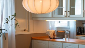 A kitchen with white cabinets, a wooden countertop, a hanging light fixture, and a window with curtains. - Top Floor Apartment with Scenic Views (Tromsø)