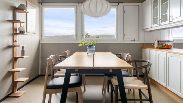 A modern kitchen with a wooden dining table, white cabinets, and a view through large windows. - Top Floor Apartment with Scenic Views (Tromsø)