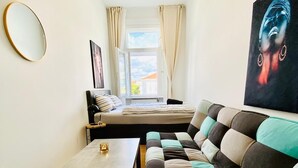 A modern bedroom with a sofa, a bed, a small table, and a window with curtains. - Comfortable 5BR Stay Near Westbahnhof (Vienna)