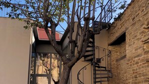 Ein Baum in einem Innenhof mit einer Wendeltreppe und einem Gebäude mit rotem Dach.