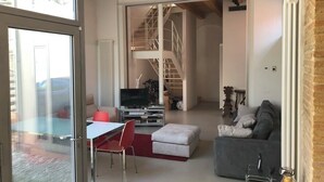 Ein modernes Wohnzimmer mit Sofa, Fernseher und Essbereich mit Tisch und Stühlen.