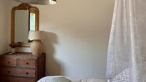 Une chambre à coucher avec un lit, une commode, un miroir et une lampe suspendue.