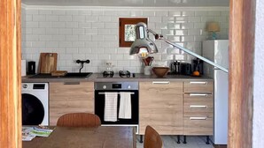 Une cuisine moderne avec des carreaux de céramique blancs disposés en motif métro, un plan de travail en bois, un évier, une cuisinière et un réfrigérateur.