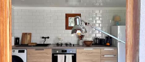 Una cocina moderna con azulejos blancos tipo metro, encimera de madera, un lavamanos, estufa y refrigerador.