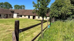 Un paysage rural avec des bâtiments traditionnels, un champ d’herbe et une clôture en bois.