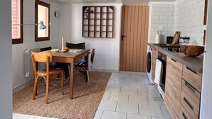 Une cuisine compacte comprenant un coin repas, une étagère intégrée et un lave-linge.