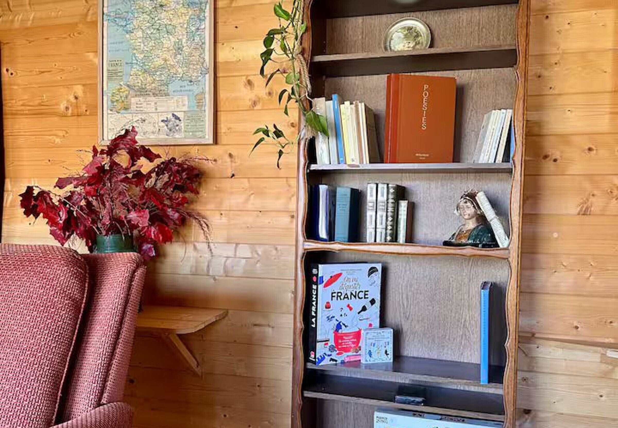 Een houten interieur met een boekenkast, een kaart en een plant.